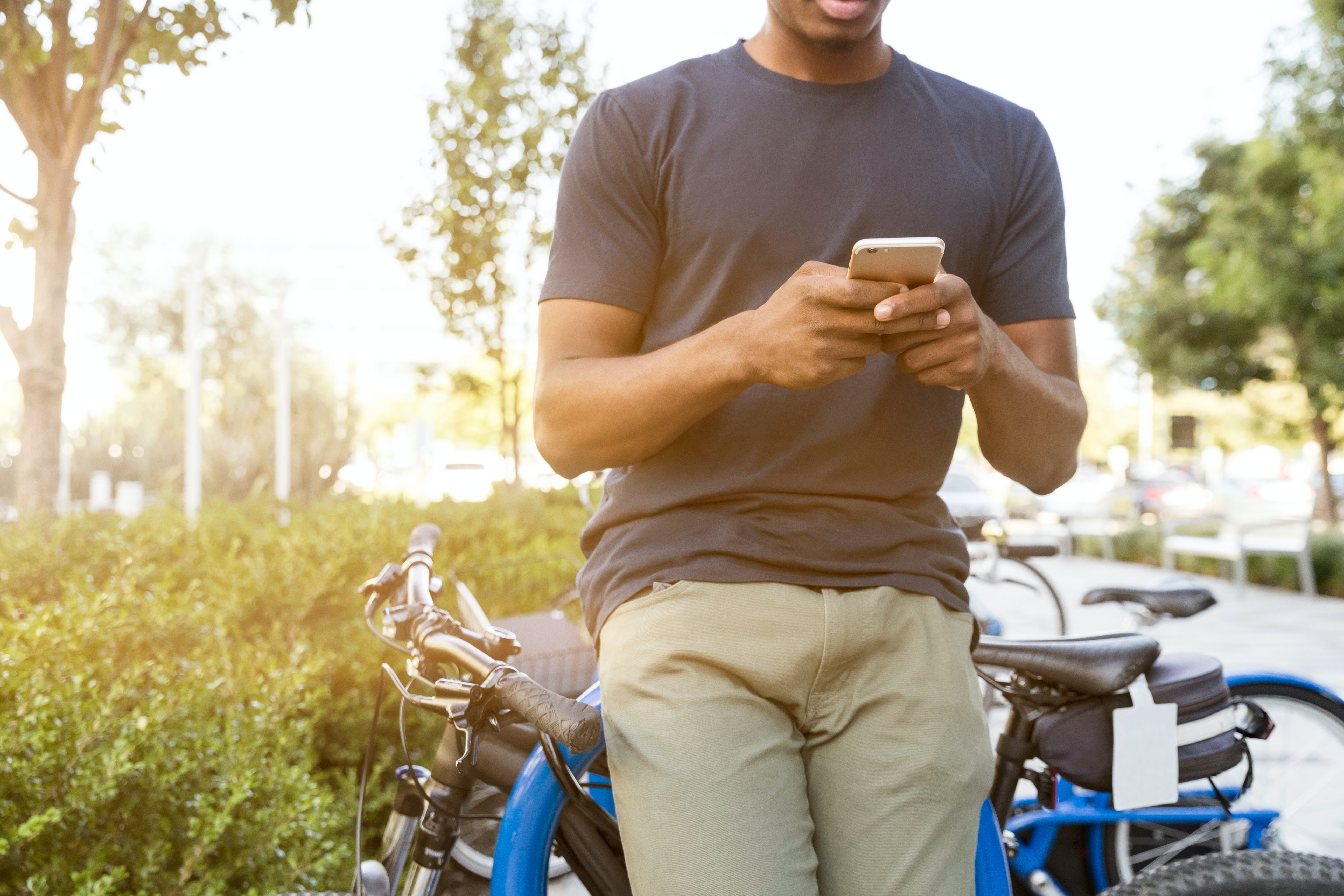 Man checking his phone while leaning against a bike.